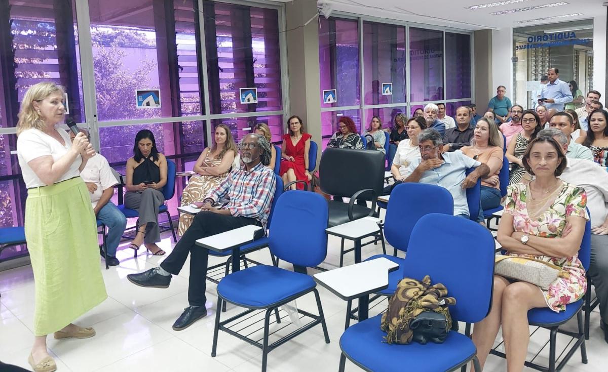Foto do público do evento dentro do auditório, vistos de frente, assistindo à fala de Ruth Reis, à frente