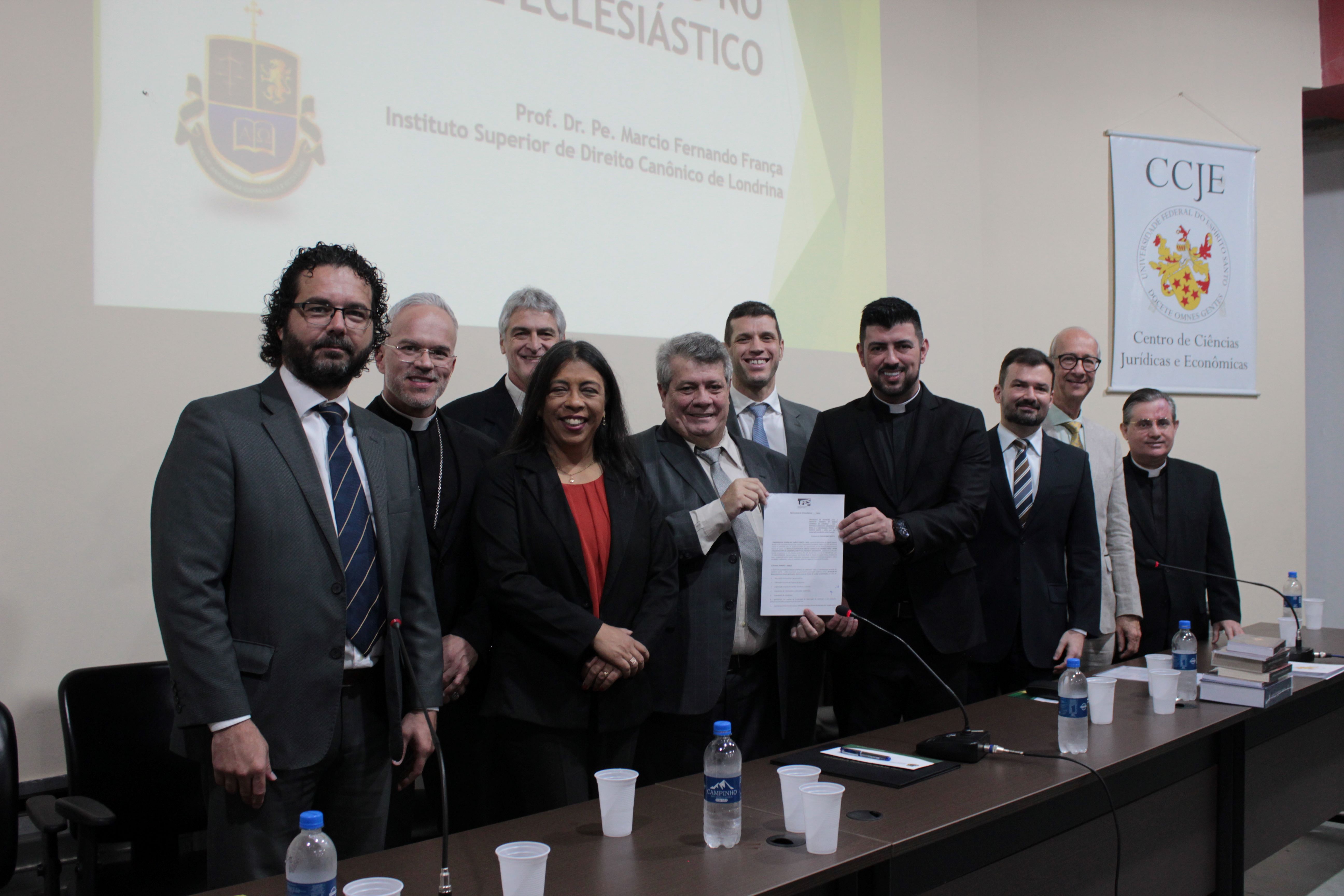 Foto das autoridades em pé, segurando o protocolo de intenções