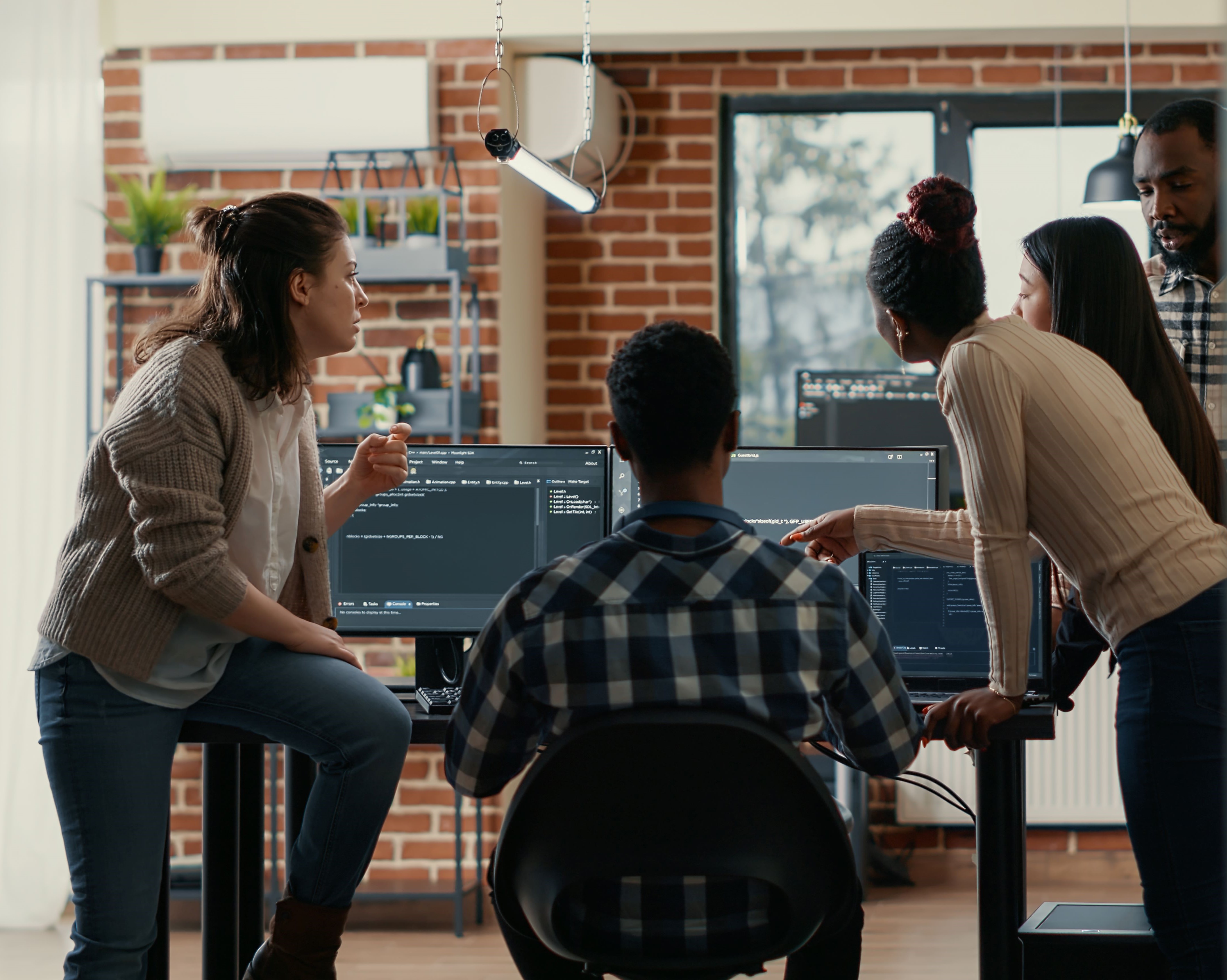 Imagem de cinco jovens, dois homens e três mulheres, discutindo em torno de um computador 