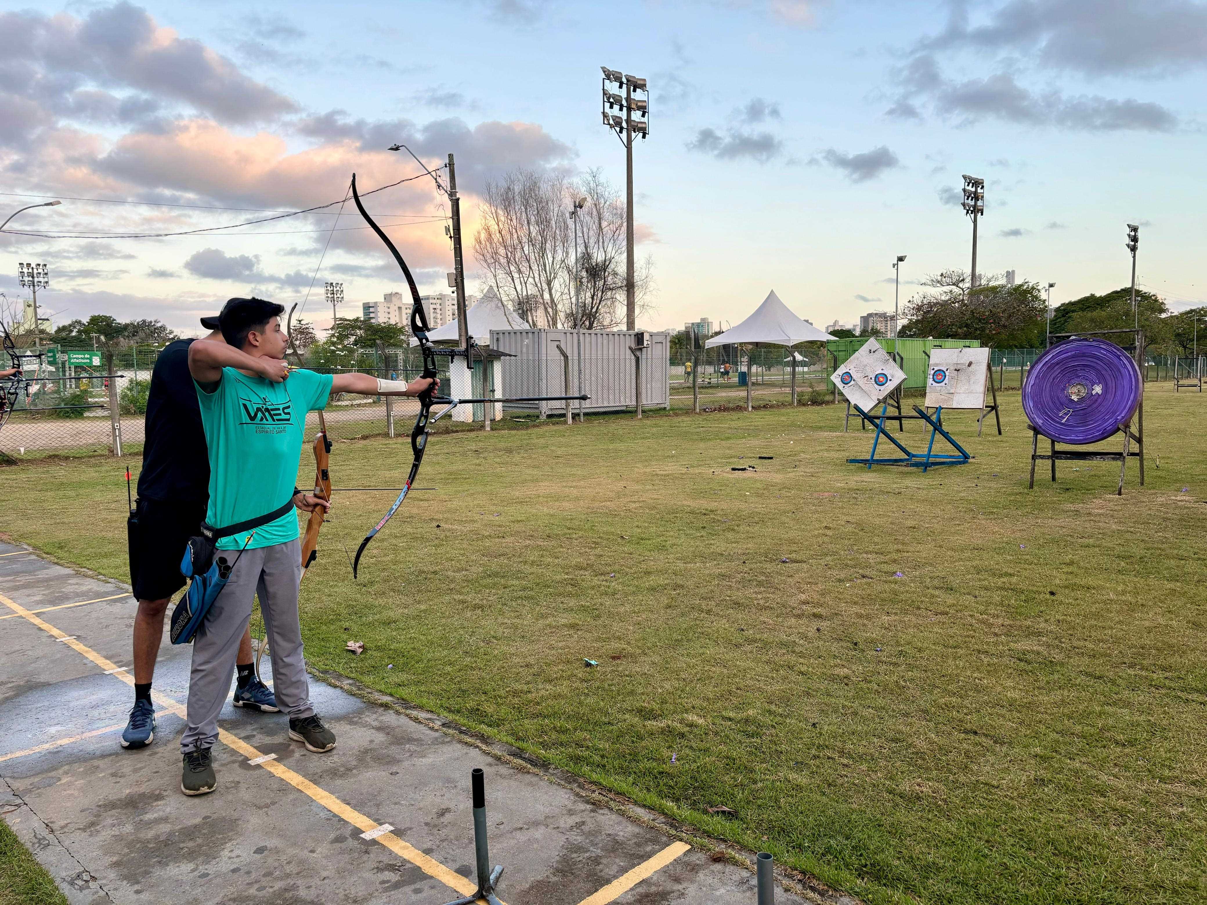 Foto de um jovem praticando no campo de tiro com arco da Ufes