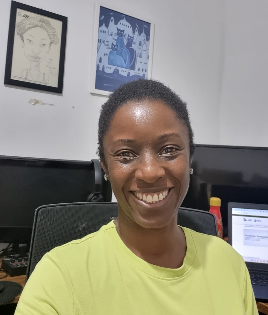 Foto da professora Tatiana Souza sorrindo para a câmera em uma sala com computadores