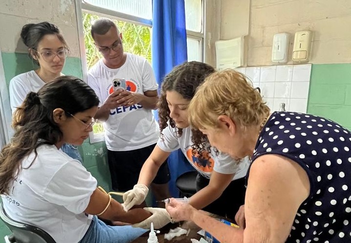 Foto de integrantes do Cepas coletando sangue de uma moça atendida pelo projeto