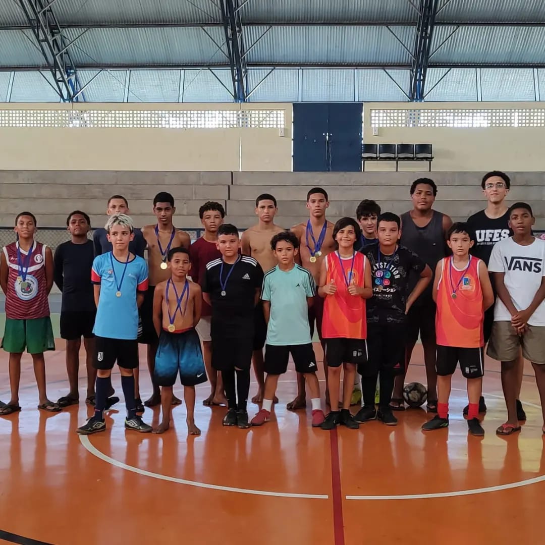 Grupo de crianças posando para foto em uma quadra de futsal 