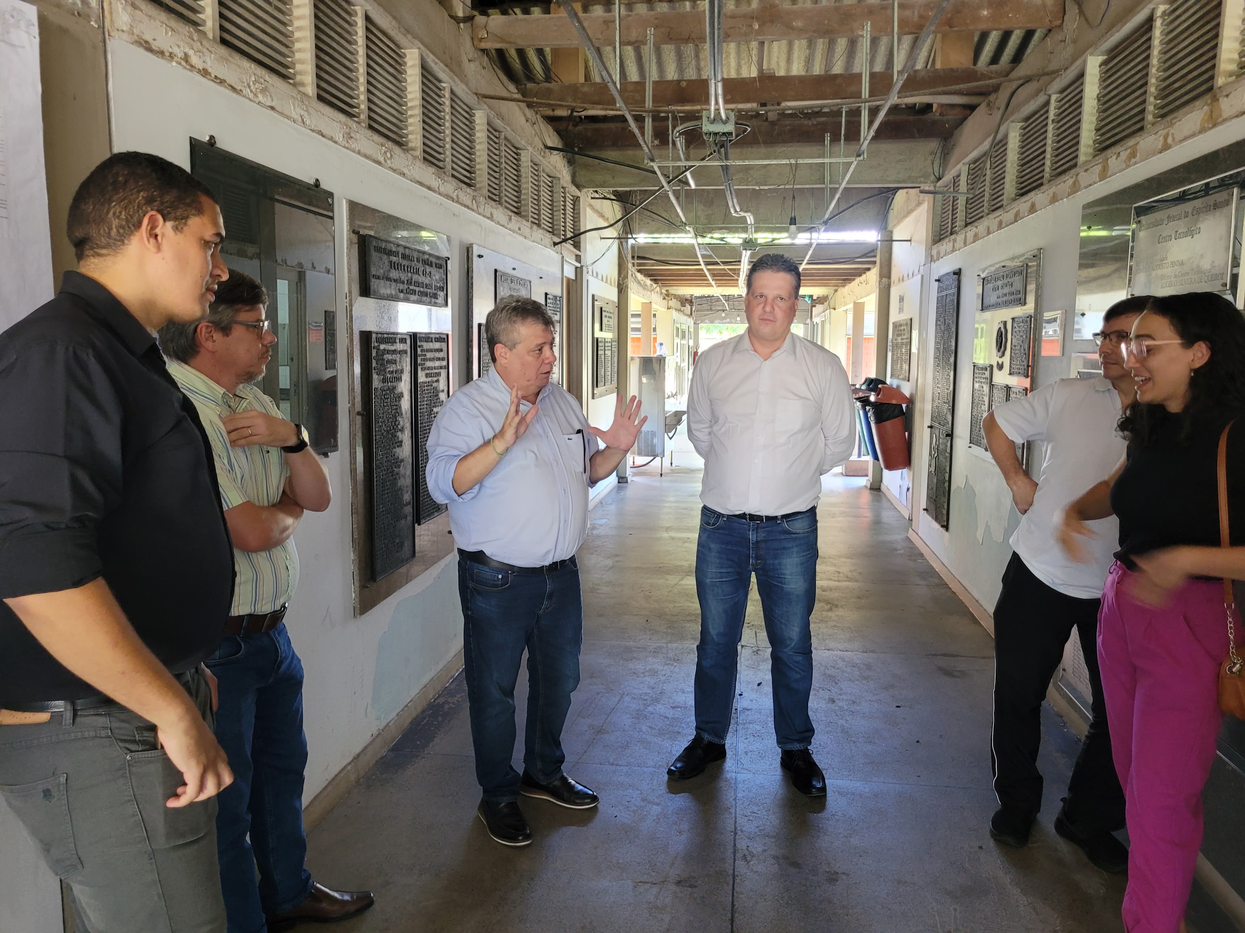 Foto do grupo na parte interior do prédio, com o reitor dando orientações