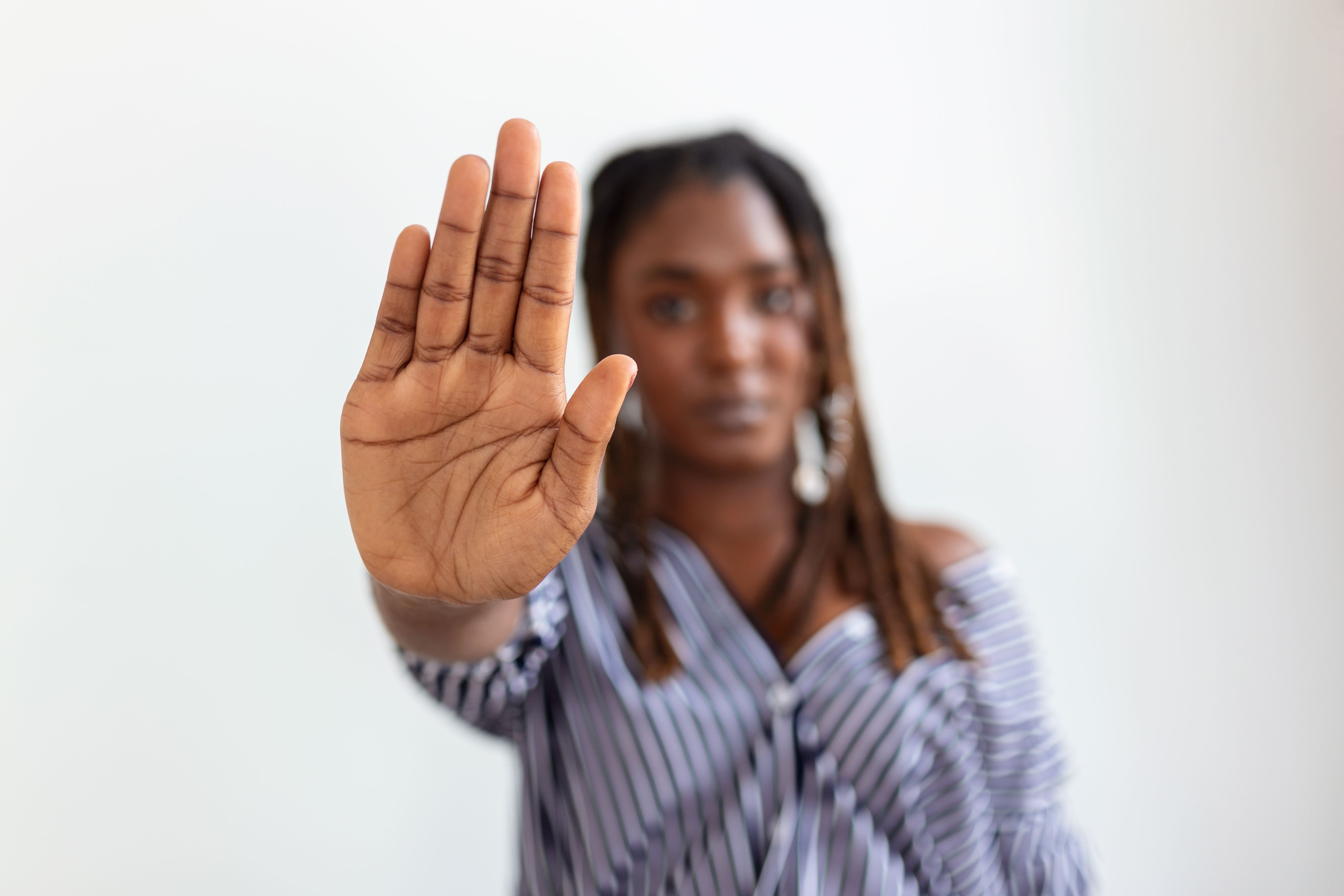 Imagem de uma mulher negra com a mão espalmada indicando "pare"