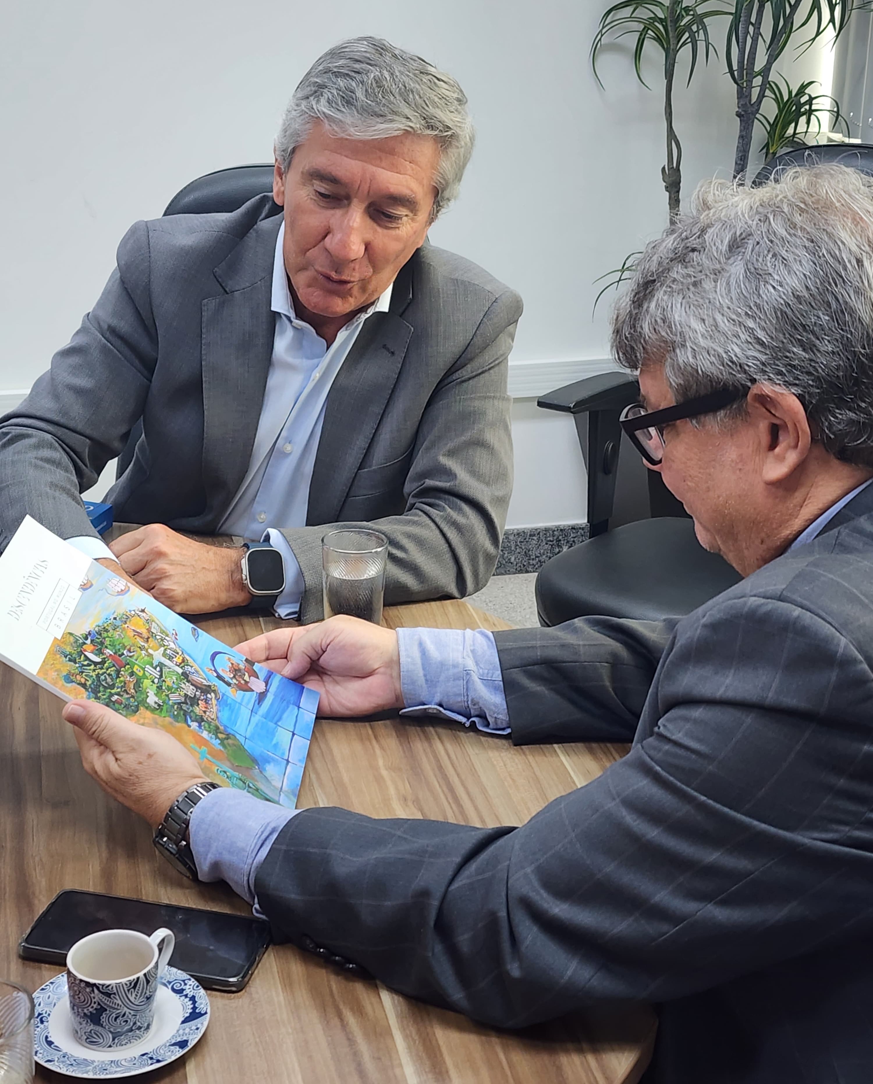 O embaixador de Portugal mostra um livro para o reitor da Ufes