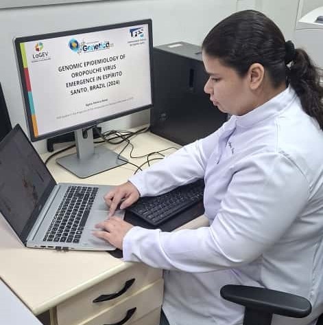 Foto da pesquisadora digitando em um notebook no laboratório