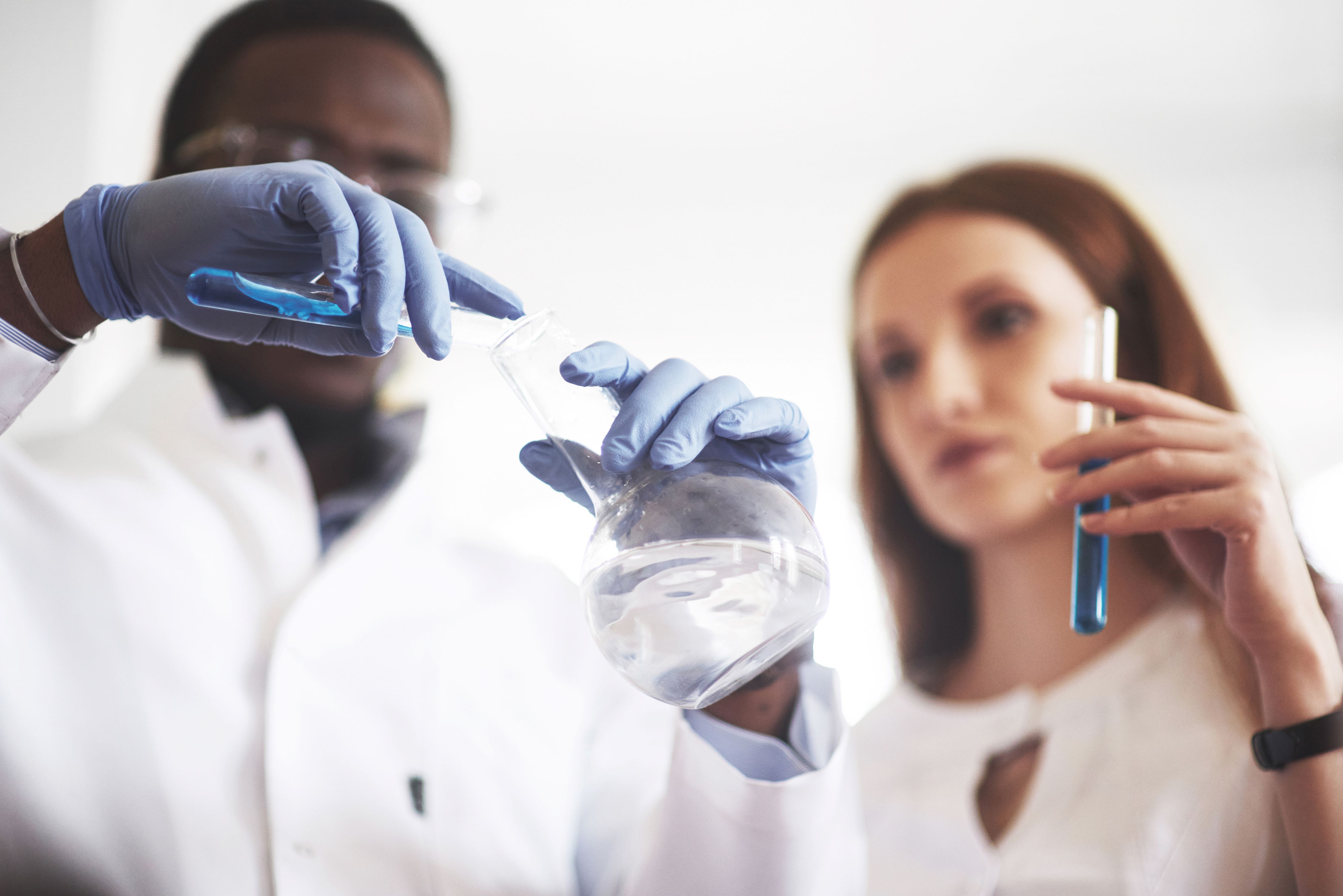 Um cientista negro e uma cientista branca em um laboratório químico fazendo um experimento