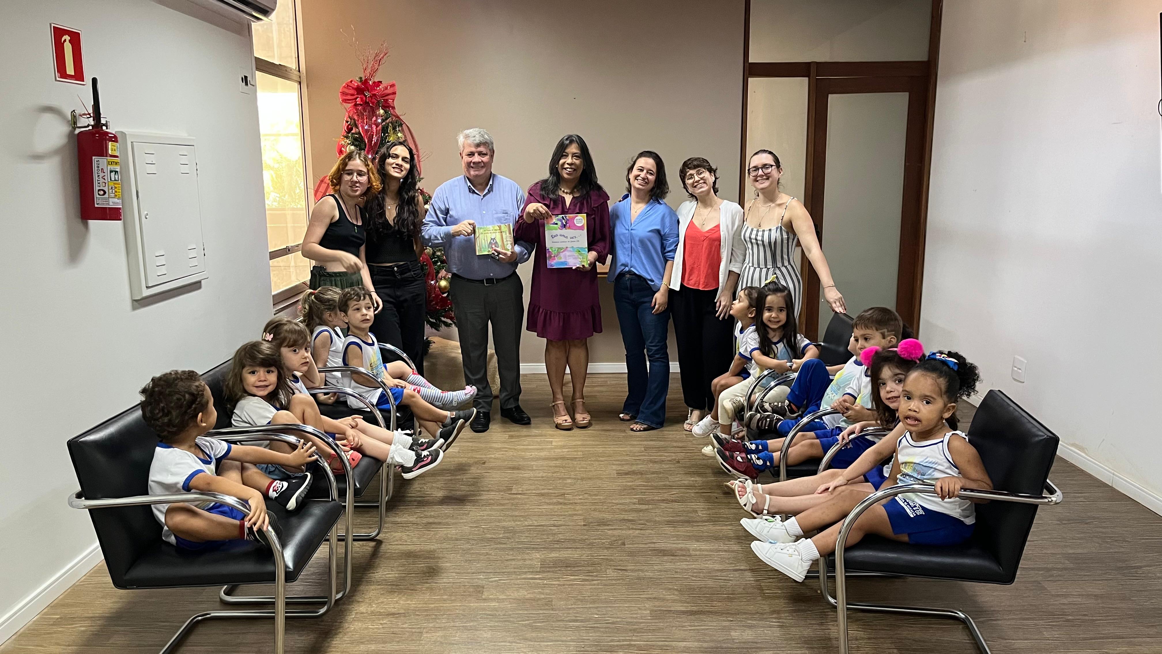 Foto do reitor e da vice-reitora com os livros em mãos e, em volta, a turma e as professoras