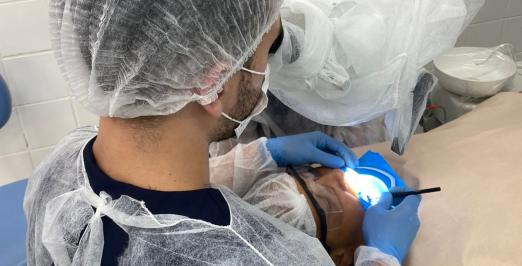 Foto de um dentista atendendo a uma pessoa no consultório