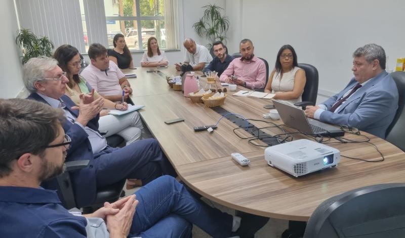 Foto da reunião, com todos os presentes sentados em torno da mesa.