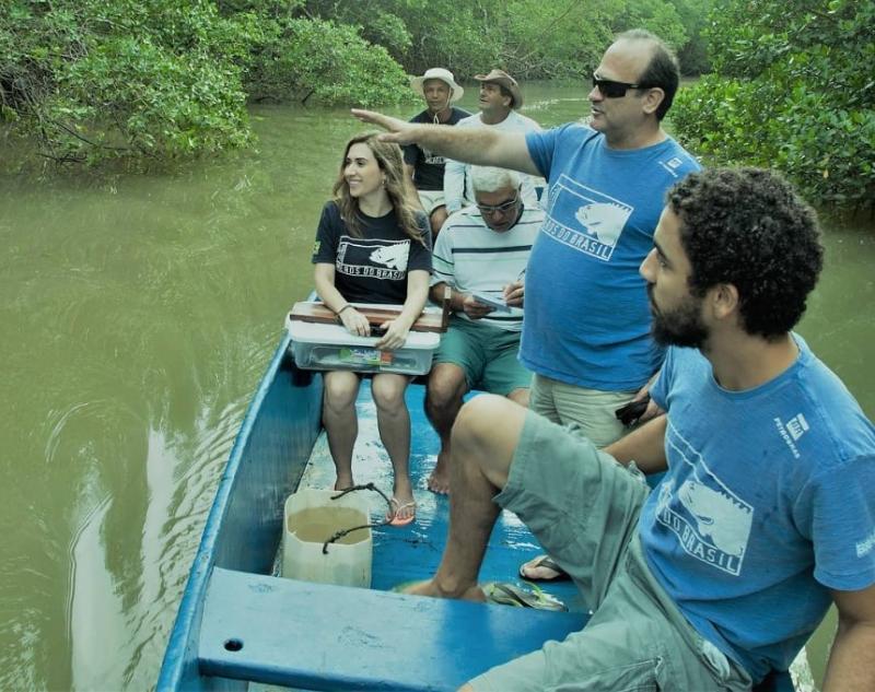 Foto do jornalista em uma canoa com pesquisadores em apuração para uma matéria