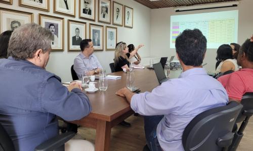 Foto dos gestores em reunião, vendo uma apresentação projetada na tela.