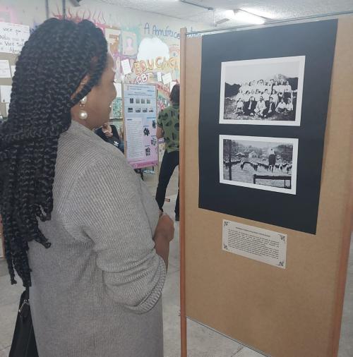 Foto de uma pessoa olhando para duas fotos da exposição