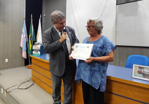 Foto do reitor entregando a homenagem à enfermeira Iracema