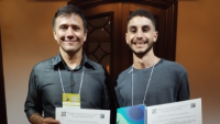 Foto de Emerson Pazeto e Rafael Herzog, ambos segurando o certificado da premiação. 