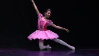 Foto de uma bailarina com roupa rosa dançando no palco