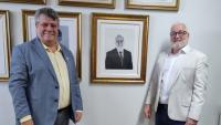 Foto: o reitor Eustáquio de Castro e o ex-reitor Paulo Vargas posam ao lado do quadro com a foto de Vargas na galeria de ex-reitores da Ufes