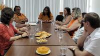 Foto da reunião com todos sentados em volta da mesa