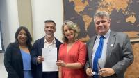 A vice-reitora, o diretor e a vice-diretora empossados, e o reitor posam para a foto. O diretor segura o termo de posse