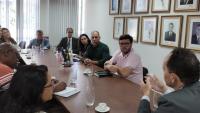 Foto dos participantes da reunião conversando em torno da mesa