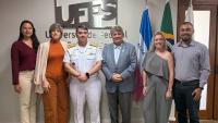 foto dos participantes da reunião em frente à parede com a logomarca da Ufes