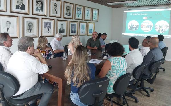 Foto dos presentes olhando para a apresentação projetada na tela