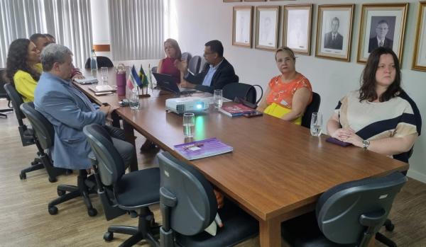 Foto dos participantes da reunião em torno da mesa, na sala de reuniões