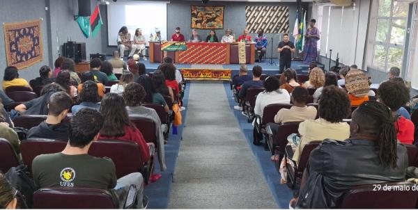Foto do auditório onde aconteceu o evento, tendo ao fundo a mesa de abertura