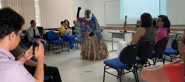 Foto de João Bananeira dançando no meio do grupo de participantes, sentado em um círculo
