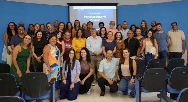 Foto de todas as pessoas presentes posando diante da tela de apresentação do novo portal