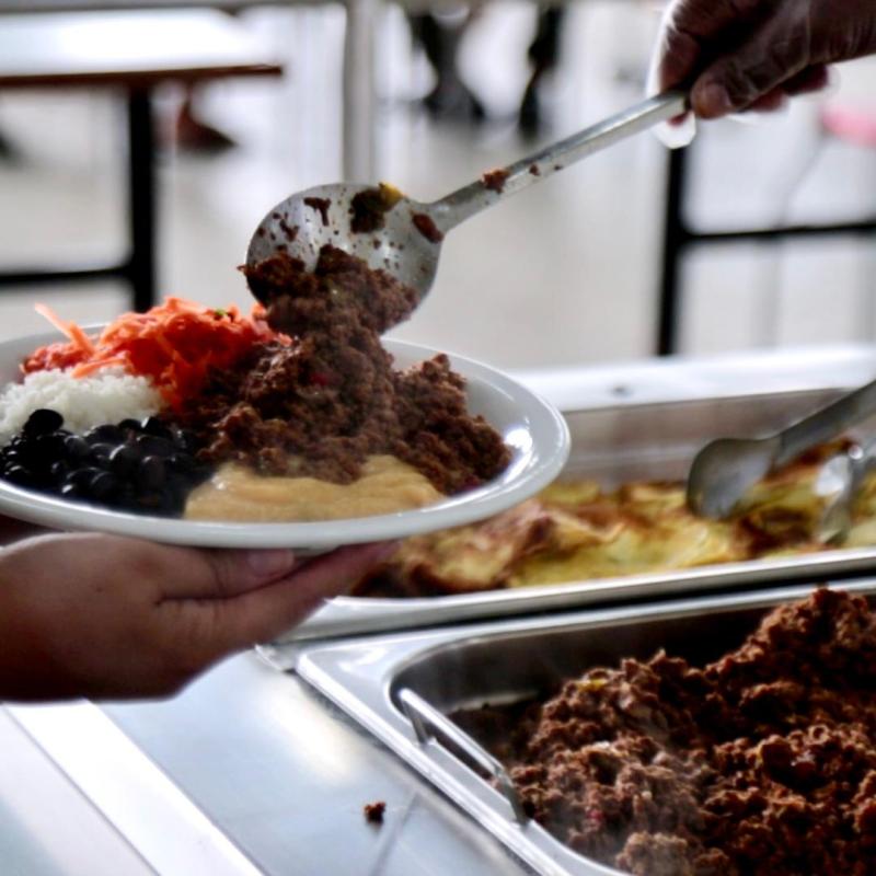 Pessoa com prato na mão sendo servida no restaurante