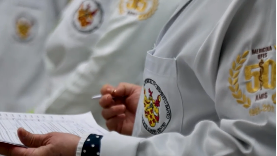 foto de um estudante usando um jaleco com a logo do curso de medicina