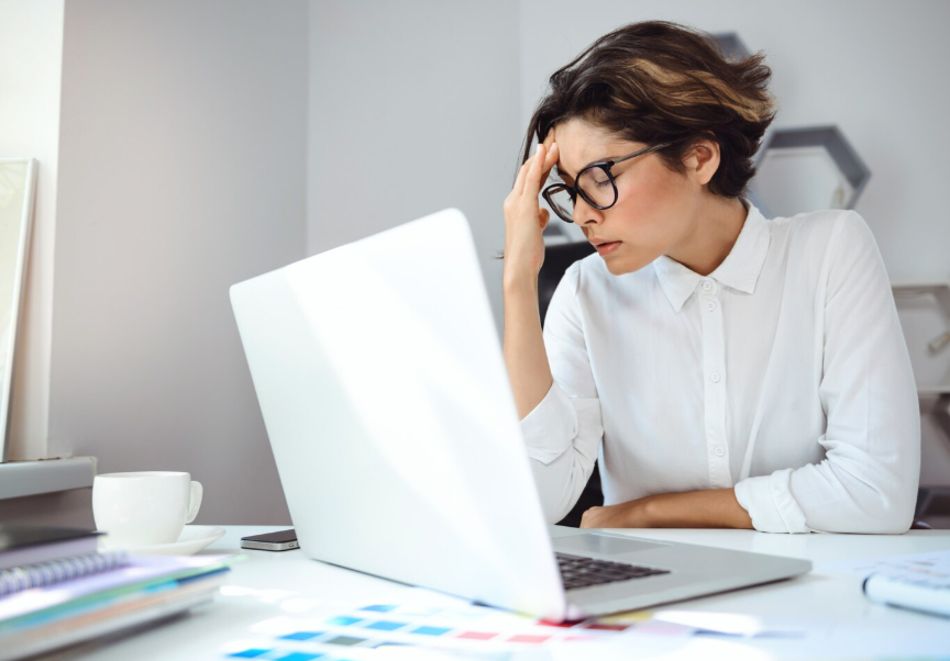 Imagem de uma mulher com a mão na cabeça em frente ao computador 