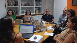 Foto dos gestores da Proex e da diretora de Governança reunidos em torno de uma mesa, recebendo a capacitação