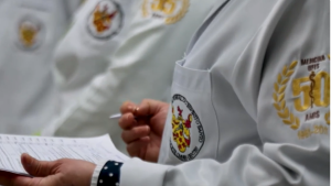 foto de um estudante usando um jaleco com a logo do curso de medicina