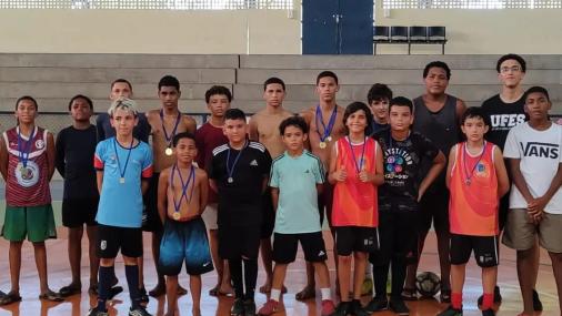 Grupo de crianças posando para foto em uma quadra de futsal 