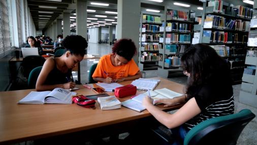 Foto de três alunas estudando em uma mesa da Biblioteca Central