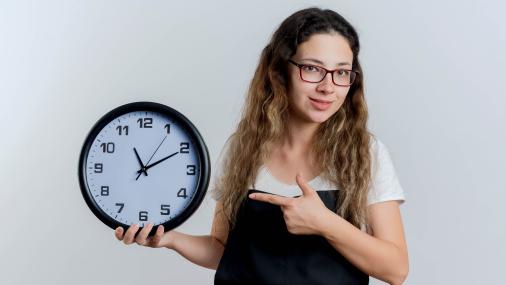 Foto de uma moça segurando um relógio redondo de parece